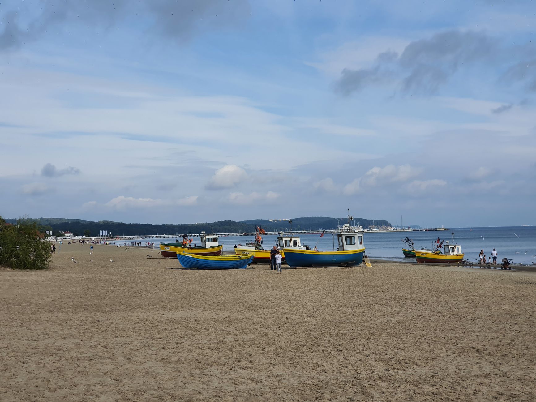 Colorful fishing boats docked on the sandy beach of Sopot, Poland, with a serene ocean backdrop.