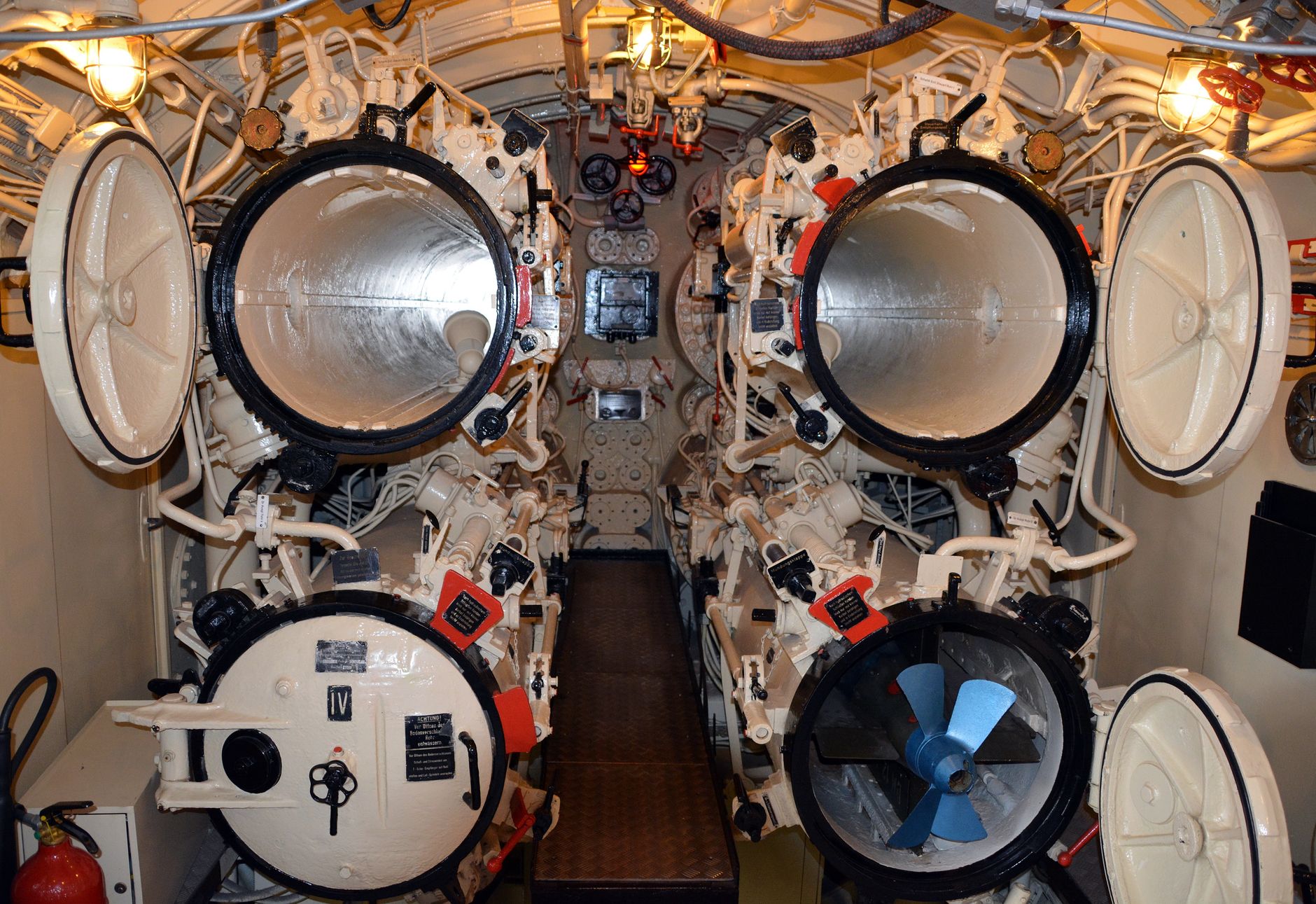 Detailed interior view of a submarine's torpedo room with open hatches.