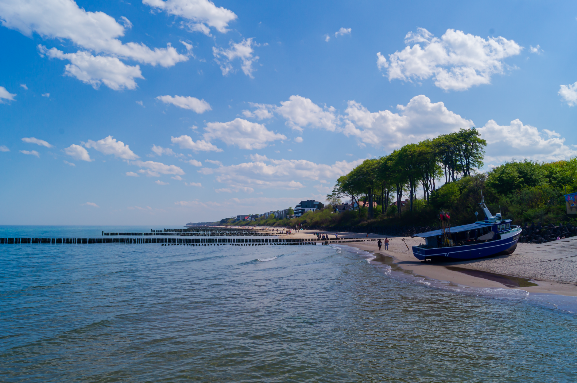 A serene view of Ustronie Morskie's coastline with a moored boat on a sunny summer day.