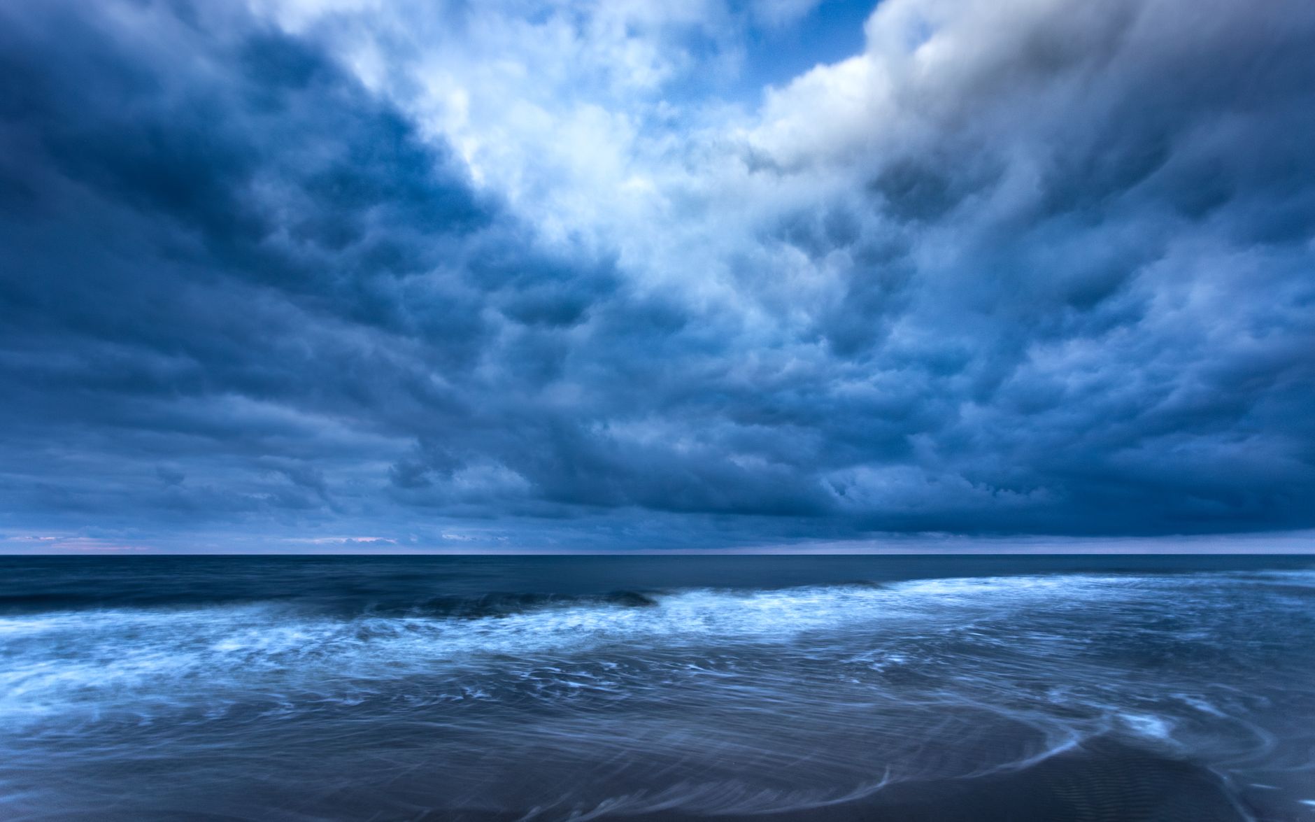 Dramatic storm clouds gather over the Gdańsk coastline, highlighting the raw beauty of nature.
