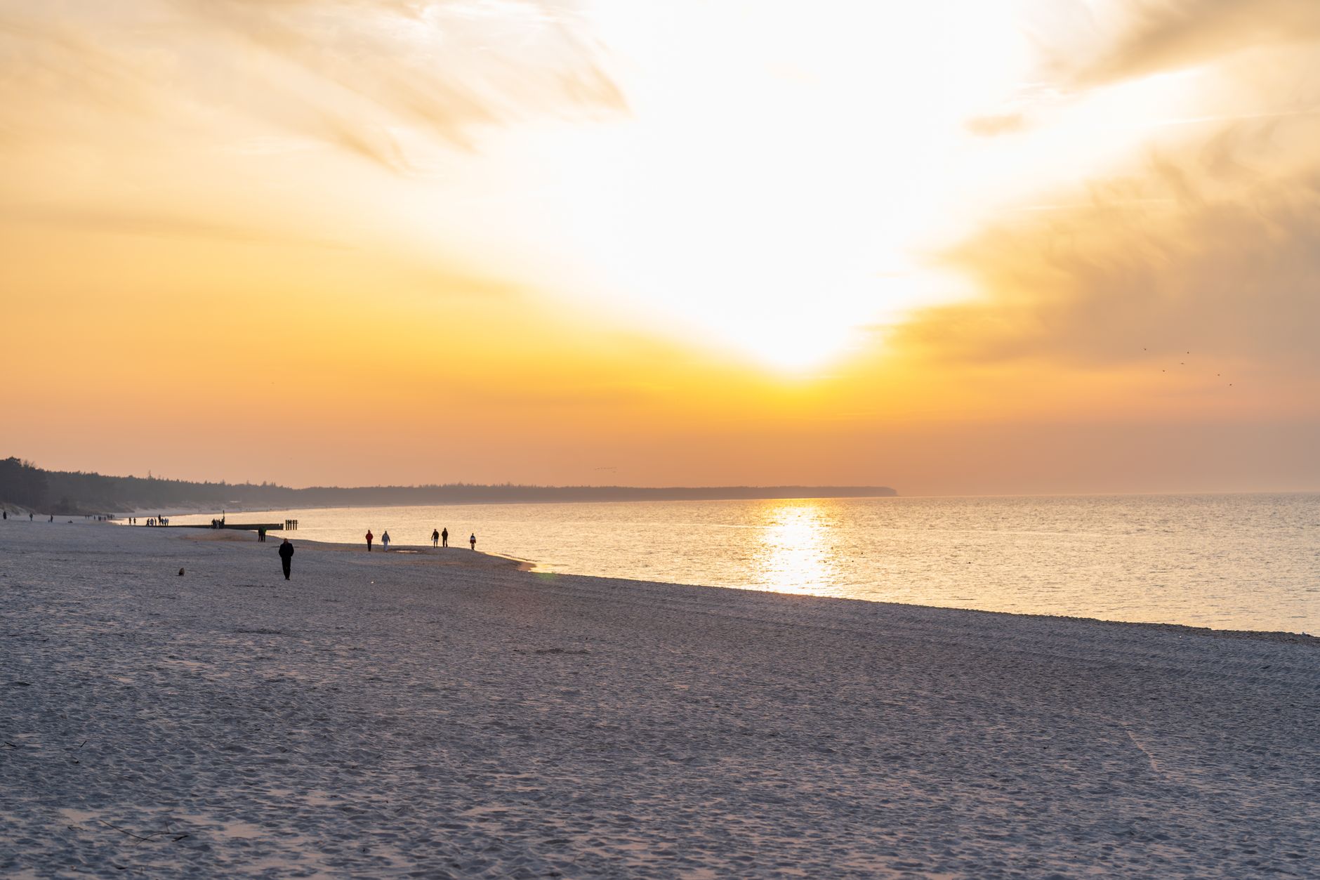 Experience the serene beauty of a sunset at Kołobrzeg Beach, showcasing vibrant colors and tranquil waves.