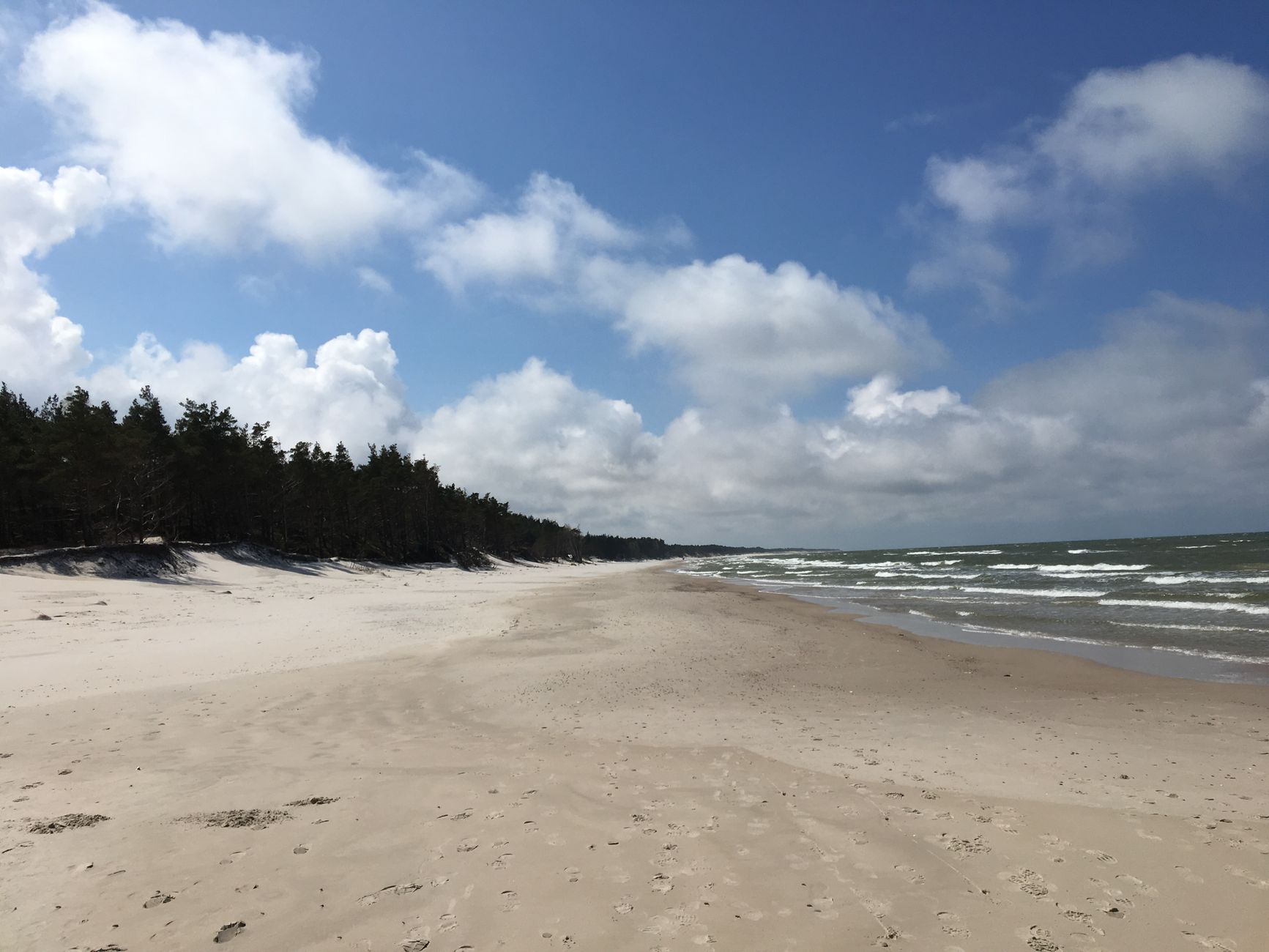 Serene beach landscape in Łeba, Poland with waves and a clear sky