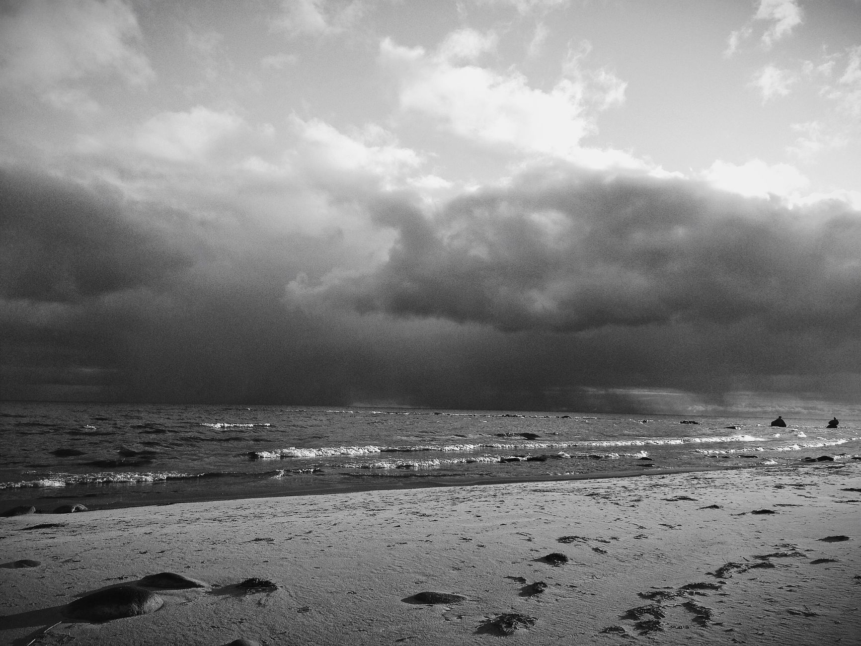 Grayscale image of a moody beach under swirling clouds, Saint Petersburg.