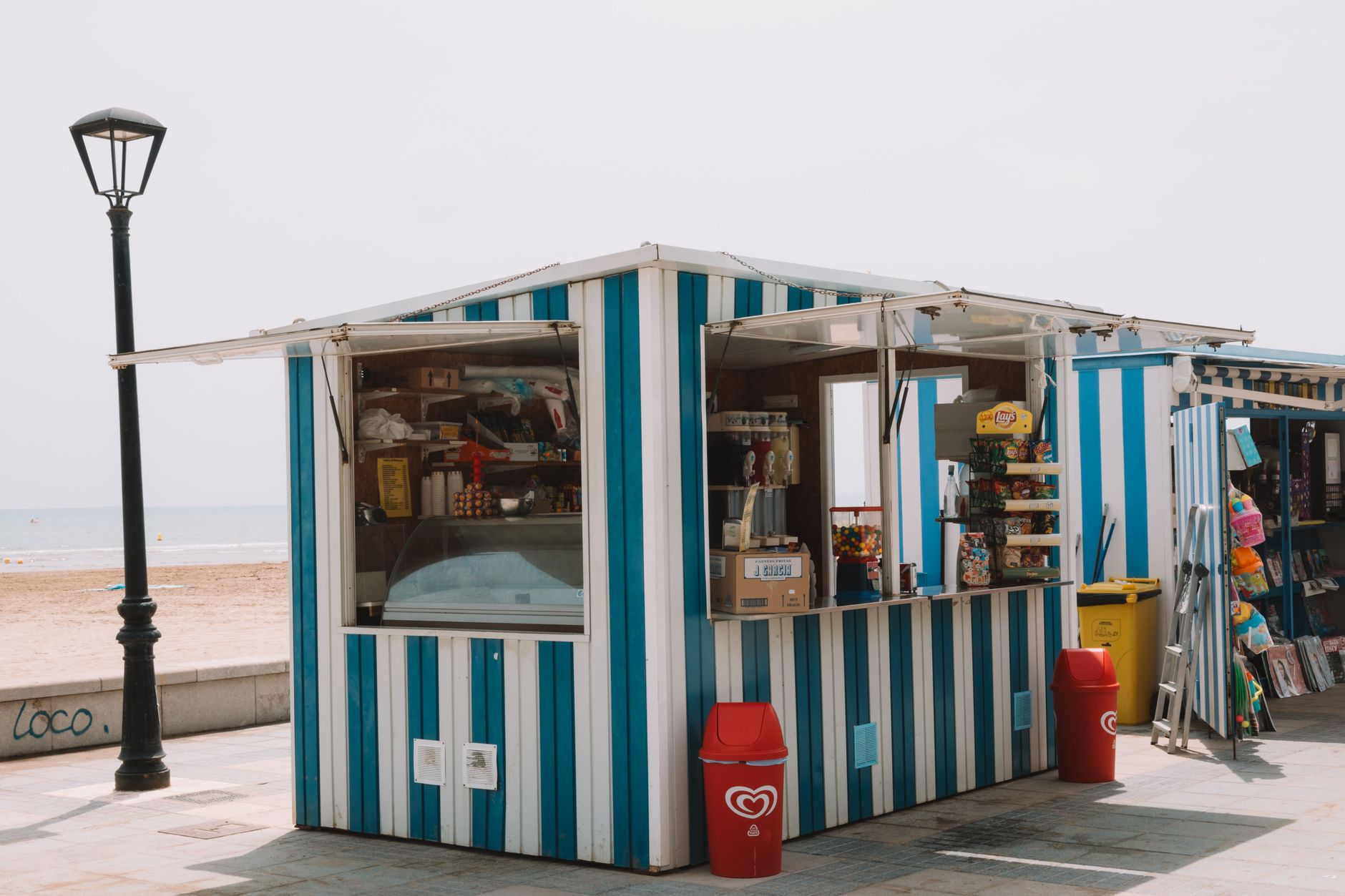 Striped snack stand on the Benidorm beach promenade, offering sweets and refreshments.
