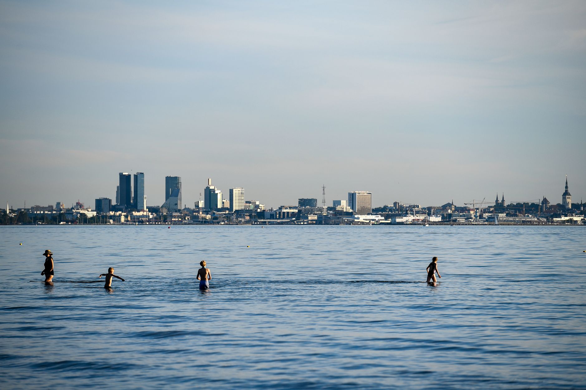 People enjoying a summer swim with the Tallinn skyline in the background.