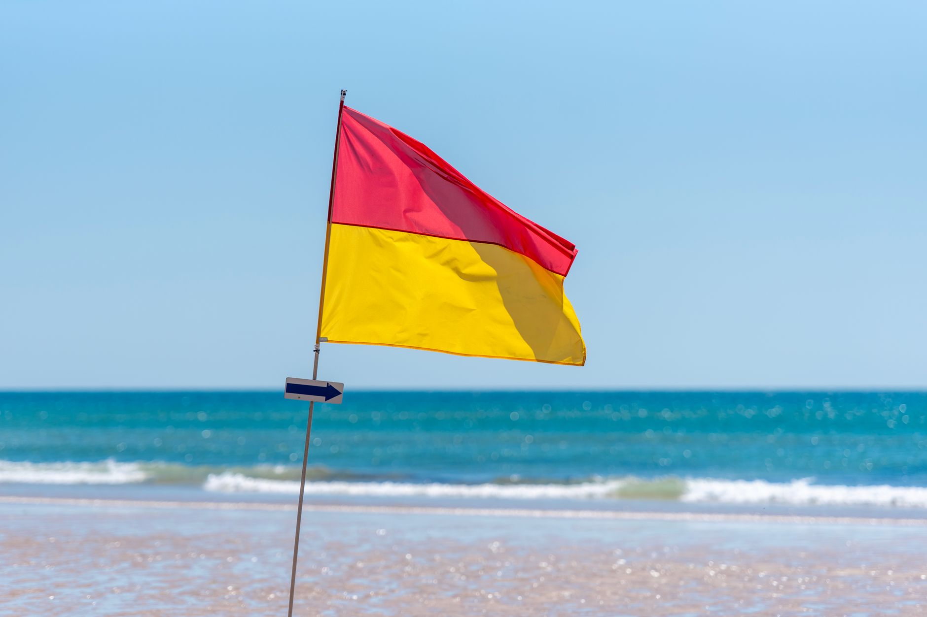 Red and yellow beach safety flag indicating swimming safety by the ocean.