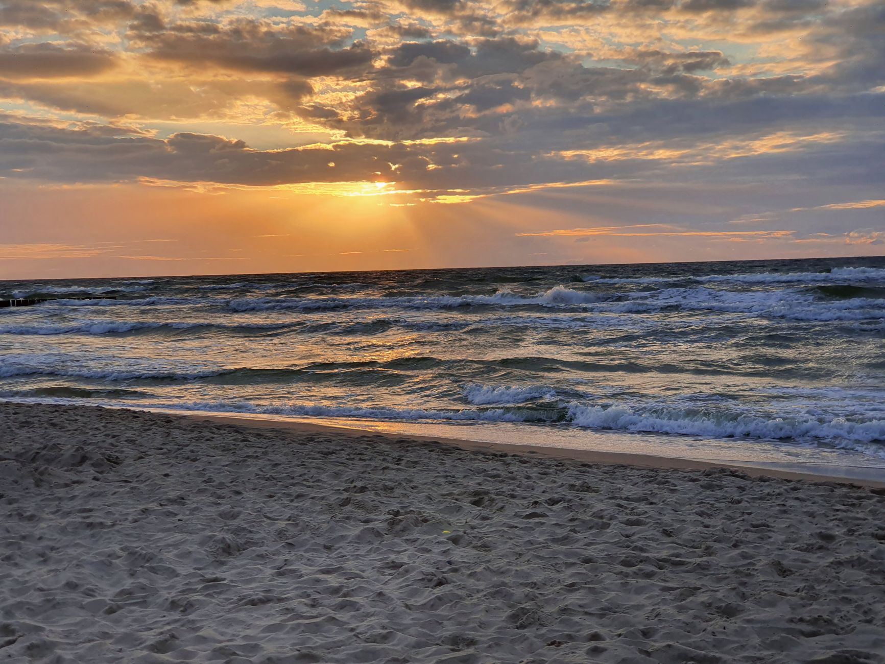 Beautiful sunset over Dziwnówek beach, capturing waves and golden skies.