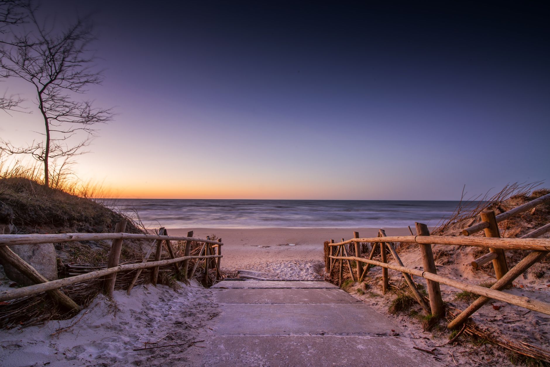 Picturesque seascape of empty pathway leading to calm water with sandy beach under cloudless sky