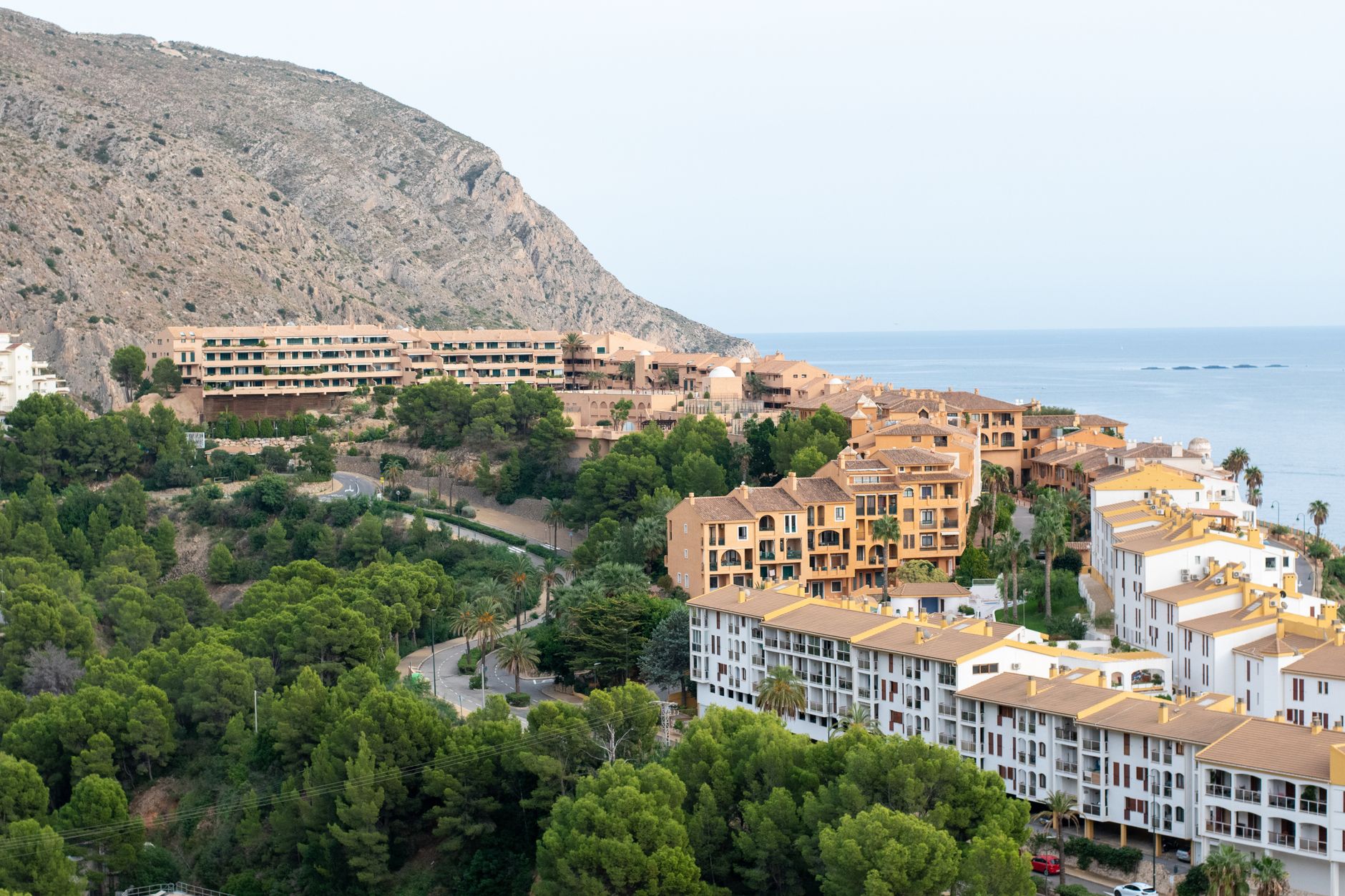 A peaceful coastal residential area with lush greenery and sea views, perfect for summer getaways.
