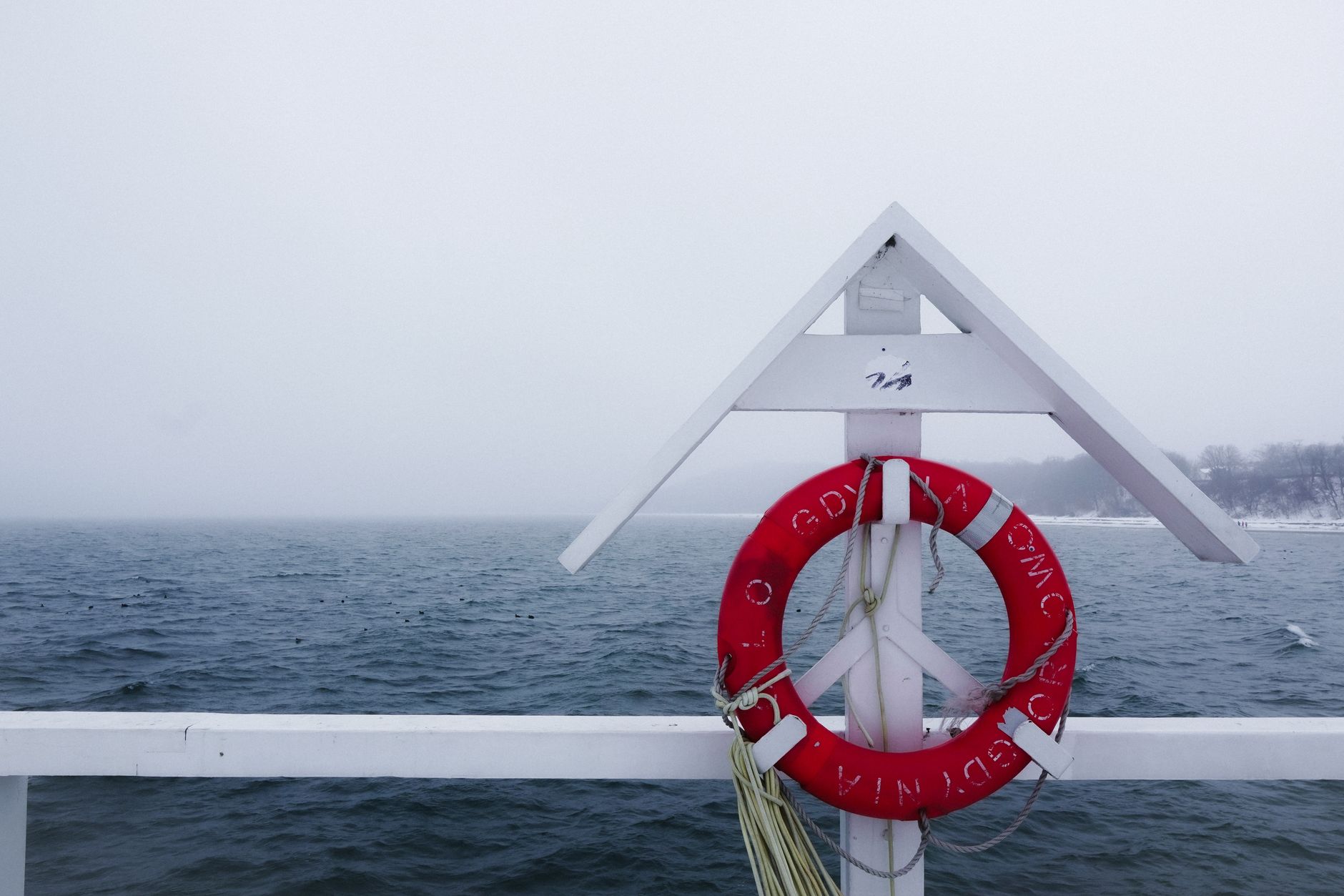 A tranquil winter view of the Gdynia pier with a lifebuoy against the cold sea.