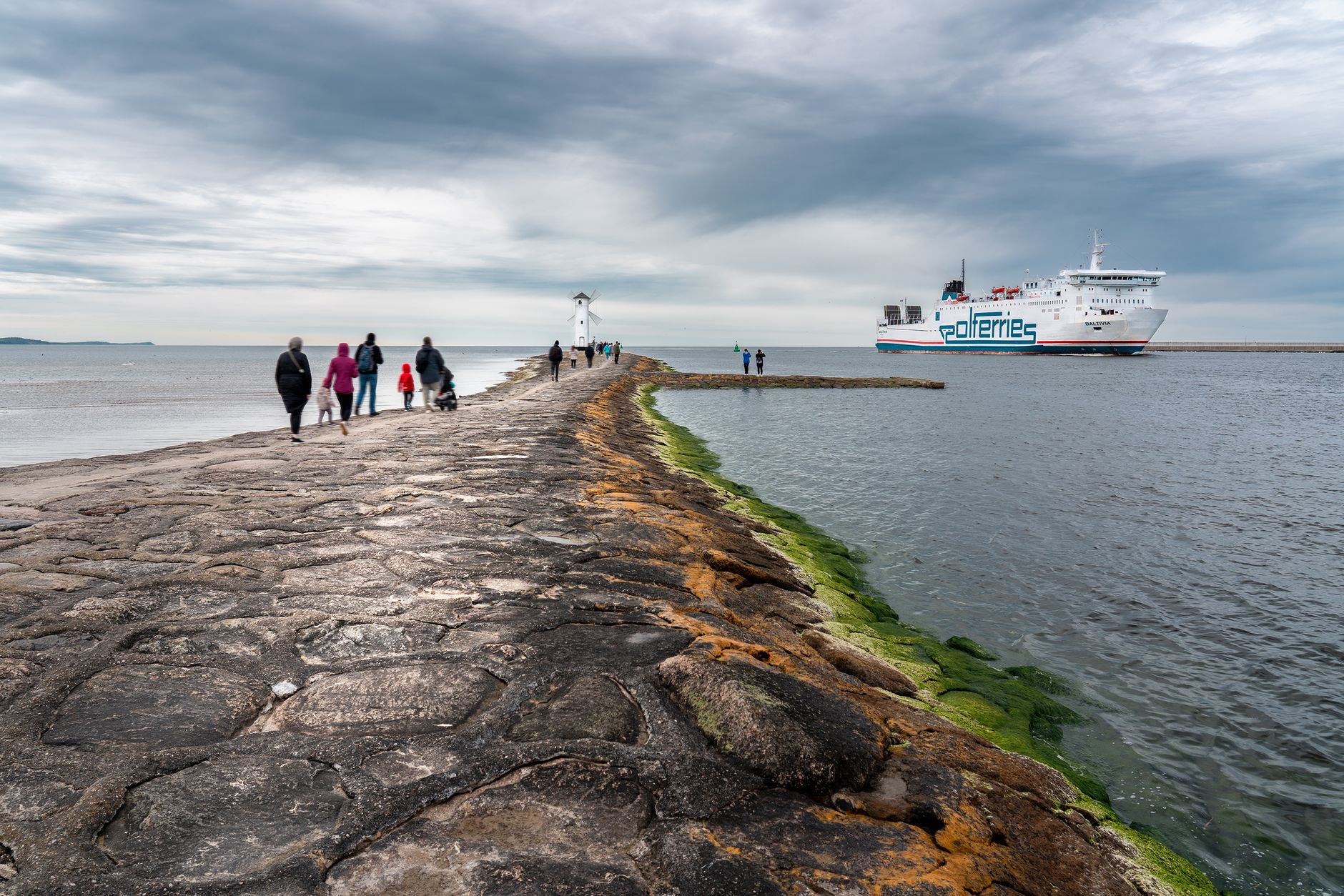 Tourists explore the iconic path leading to the Stawa Młyny lighthouse in Świnoujście, Poland.