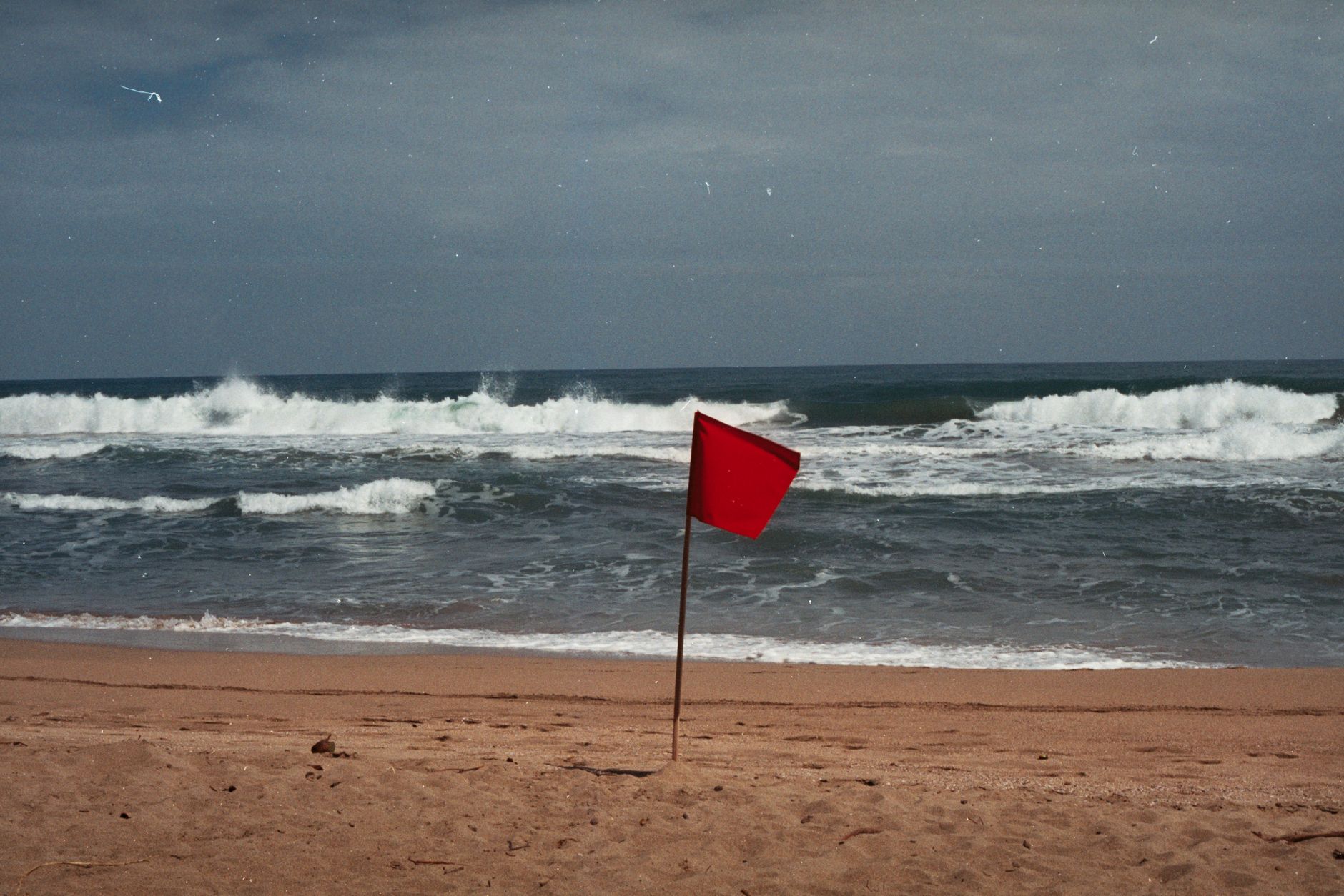 A red flag signals dangerous conditions on a Costa Rican beach. Stay cautious.