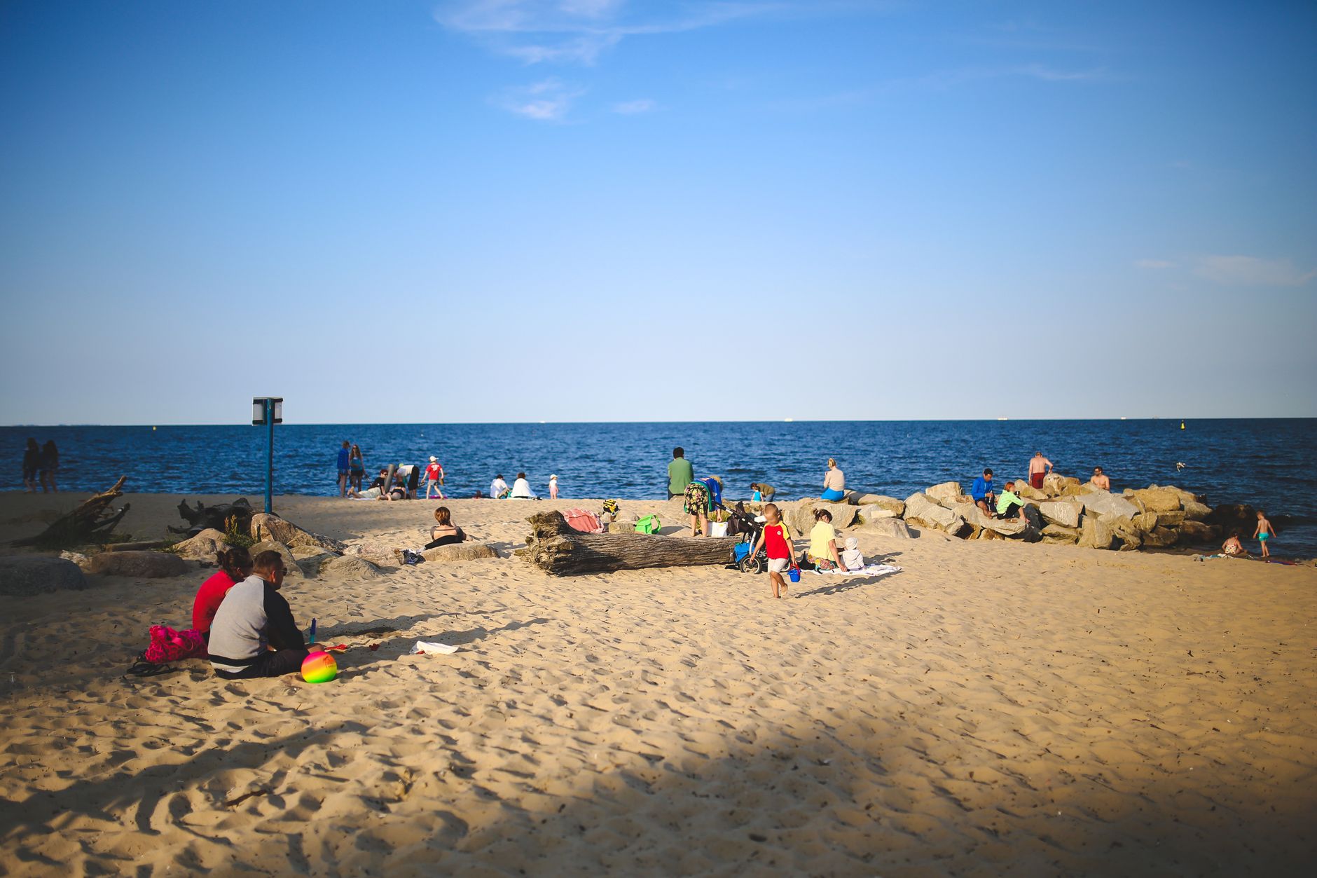 Families enjoying a sunny day on a sandy beach by the sea, perfect for a summer getaway.