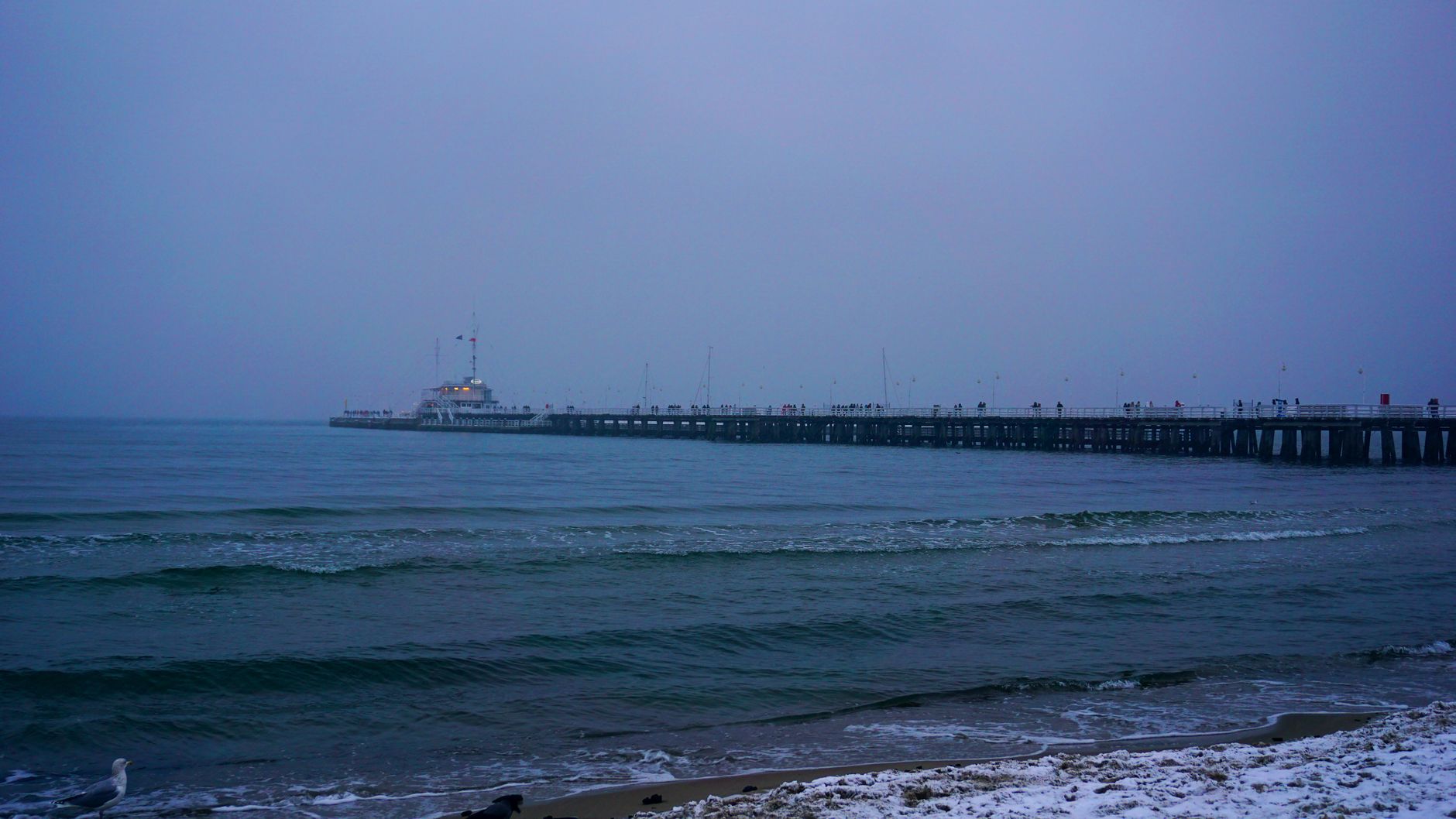 Capture of Sopot Pier with gentle waves under a moody winter twilight sky.