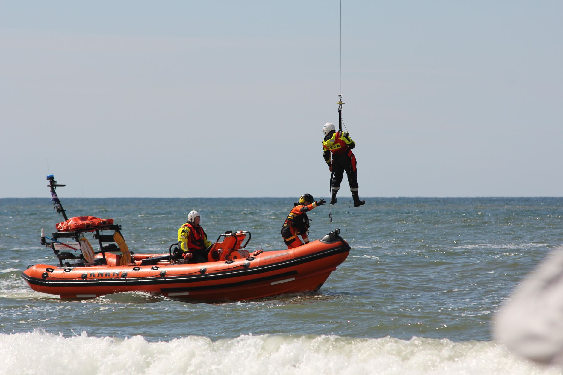 Rescue workers in action with lifeboat and helicopter on the open sea.