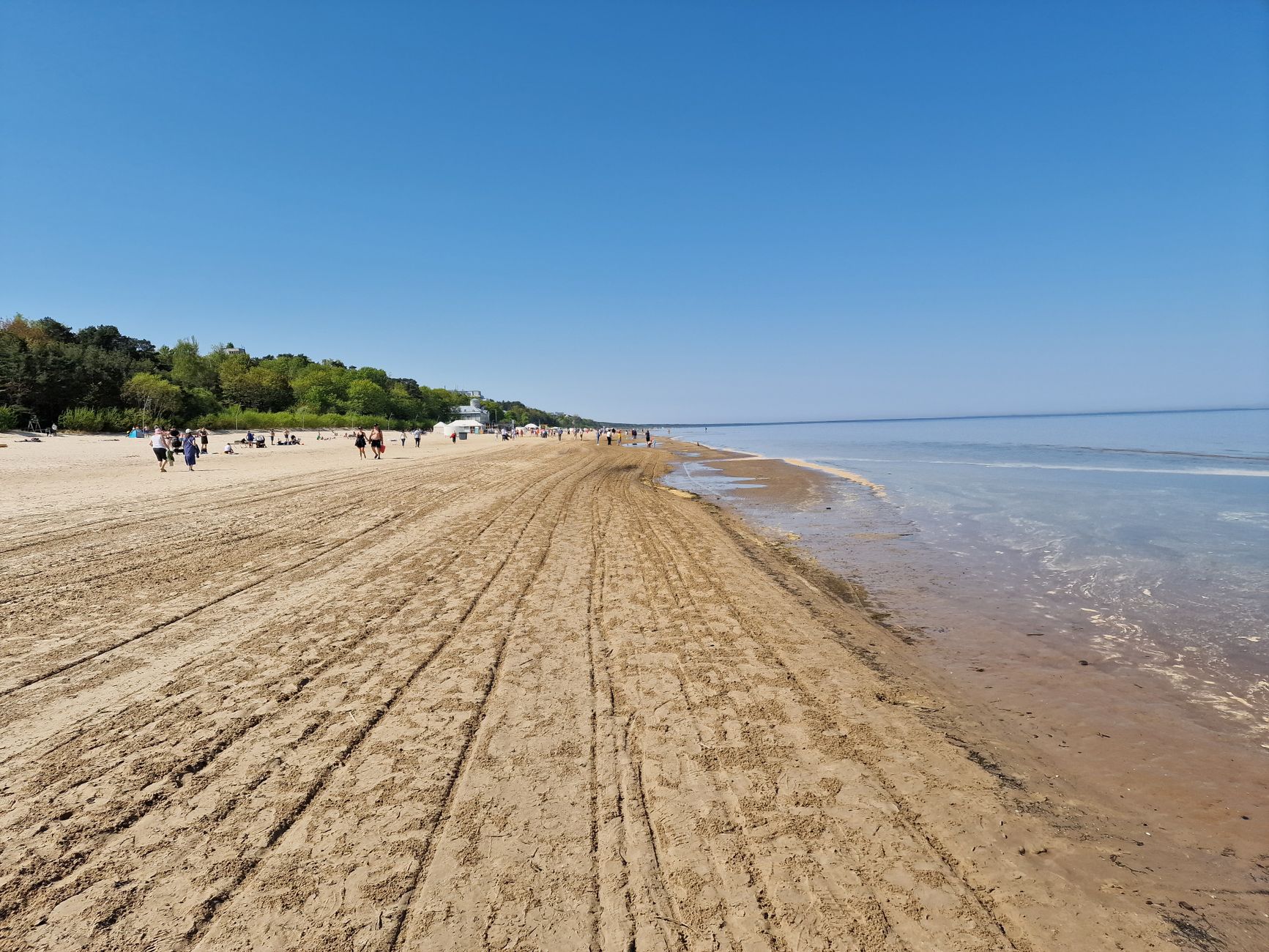 Explore the serene sandy shores of Jūrmala, Latvia, under a clear blue sky.