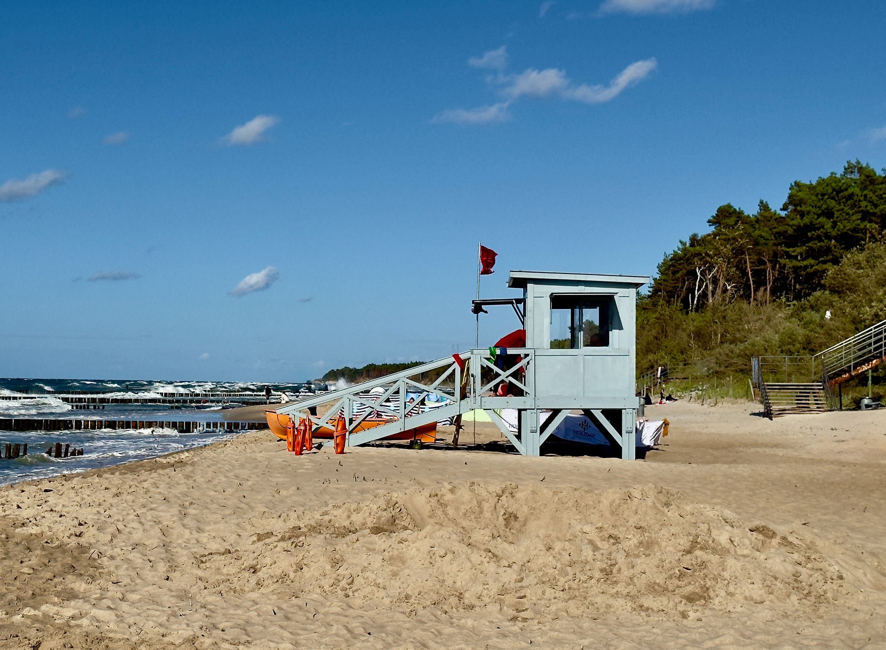Lifeguard station on a sandy beach in Ustronie Morskie with waves and blue sky.