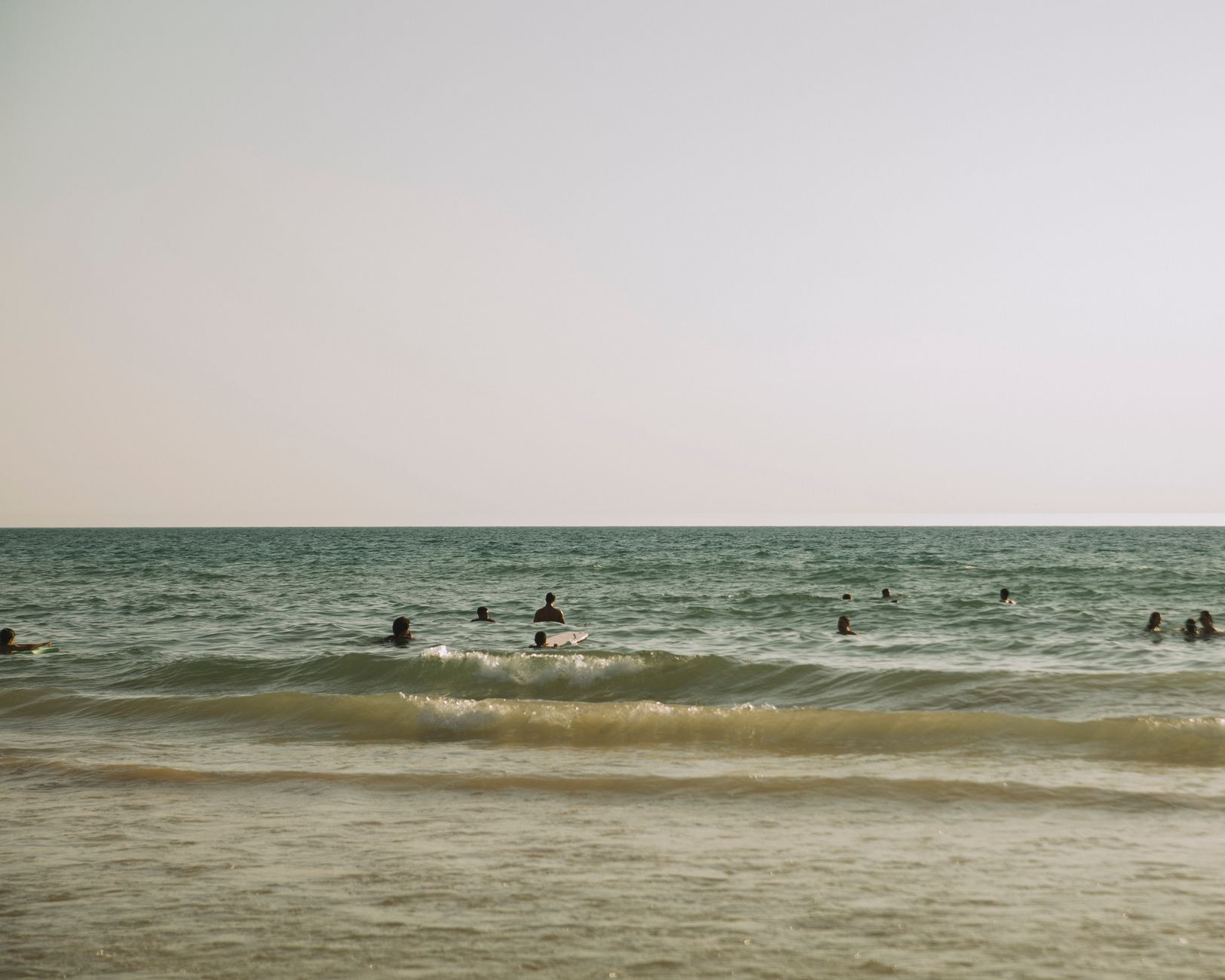 People enjoying a relaxing swim in the sea under a clear sky, perfect for a summer vacation.