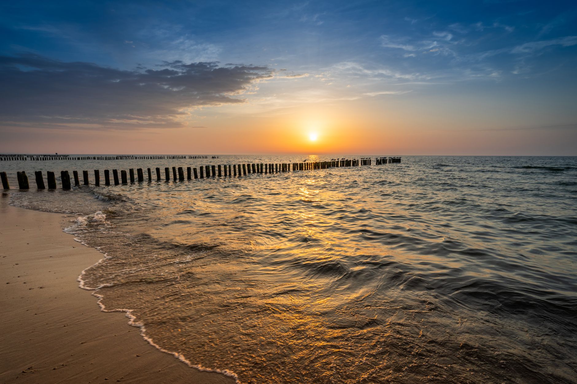 Captivating sunset over the Baltic Sea with golden reflections on the beach at Mielno, Poland.