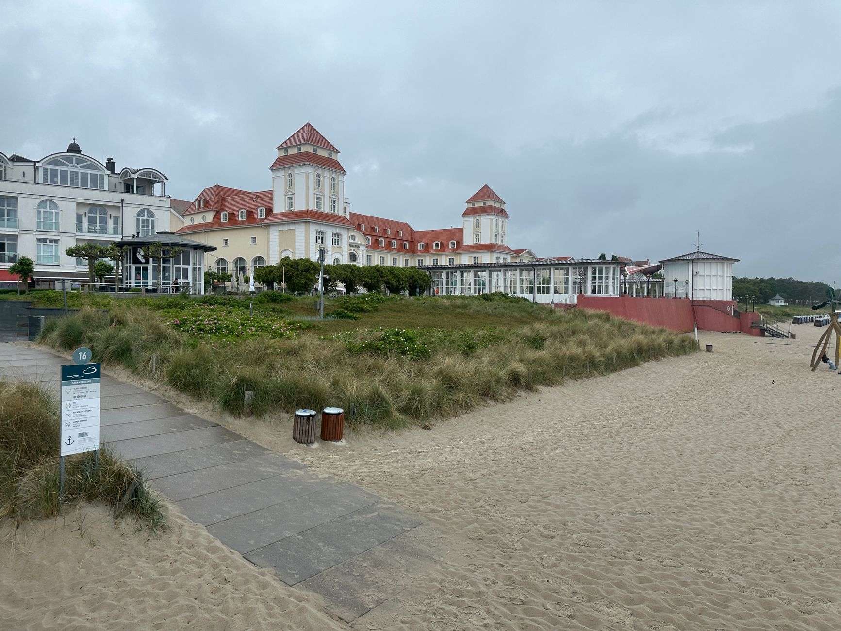 Picturesque view of an elegant hotel by the beach with cloudy skies.