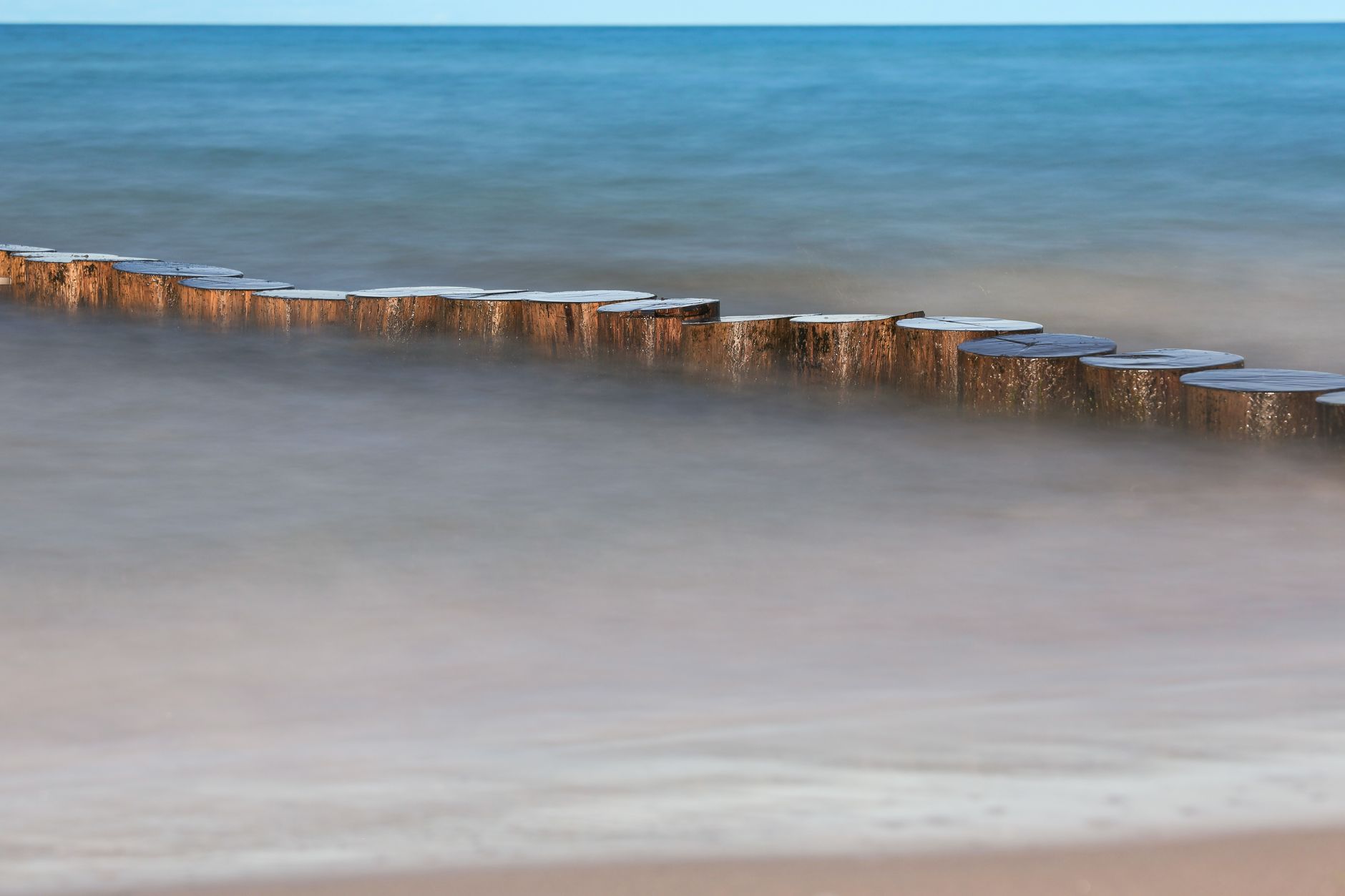 Tranquil Baltic Sea scene with wooden breakwater, capturing peaceful coastal vibes in Prerow, Germany.