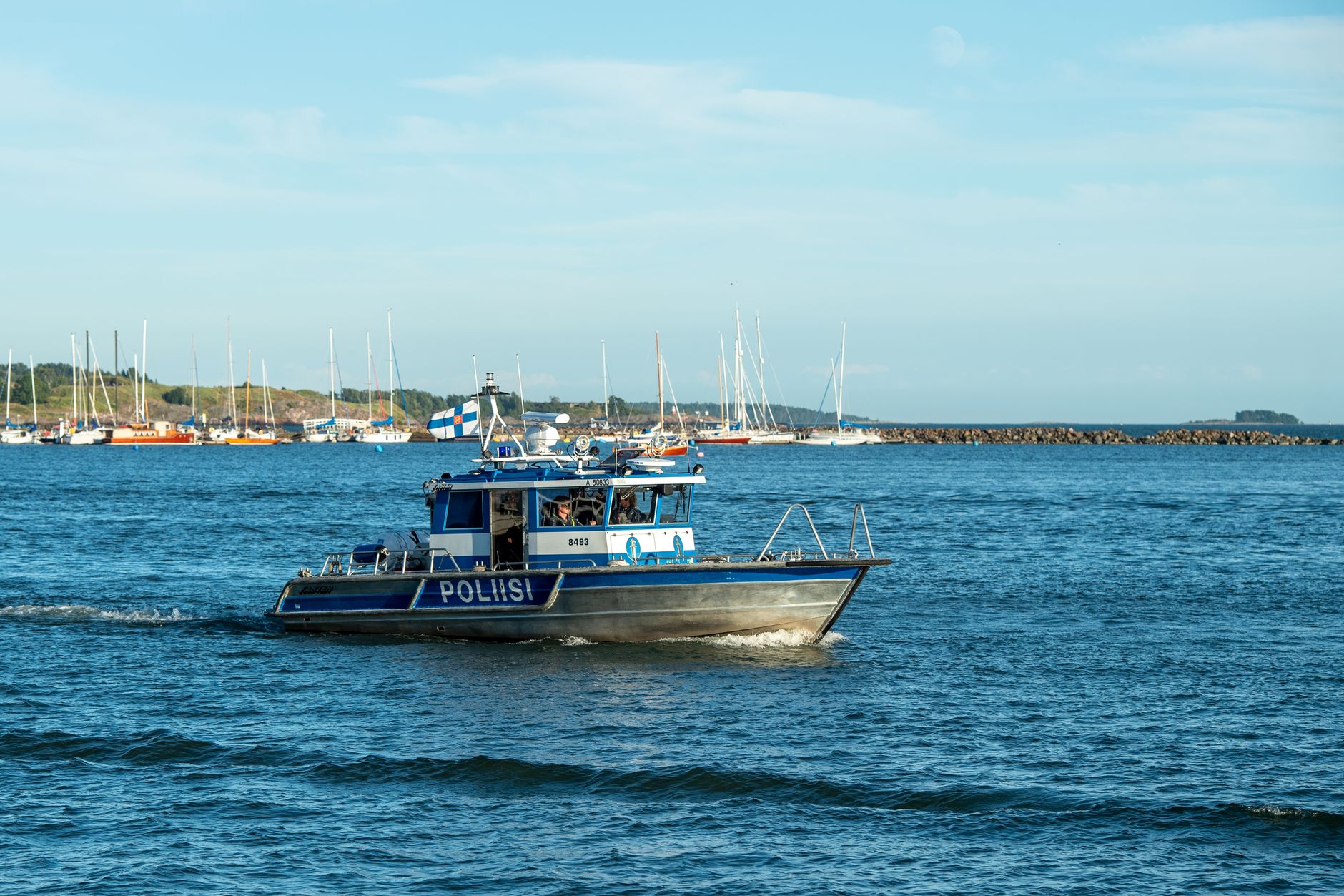 Finnish police boat patrolling Helsinki harbor in clear spring weather, ensuring maritime safety.