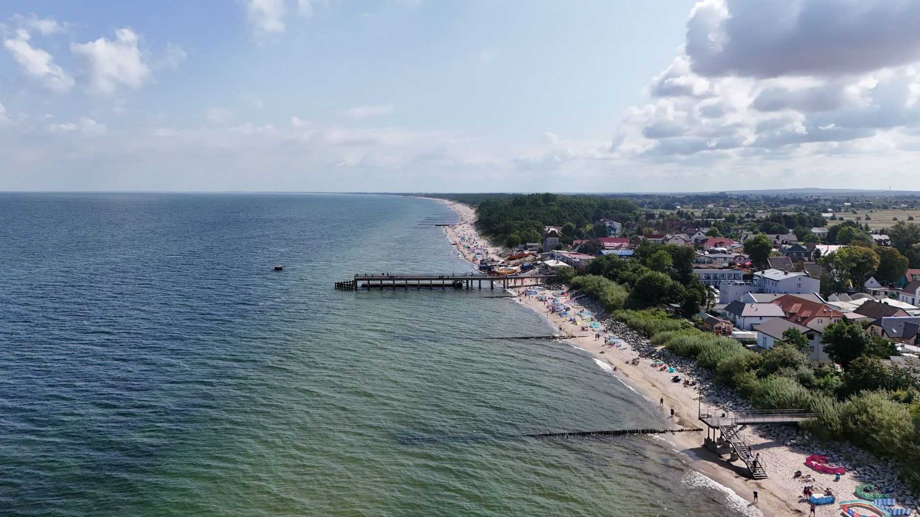Aerial view of a picturesque coastal town with beach, pier, and clear skies.