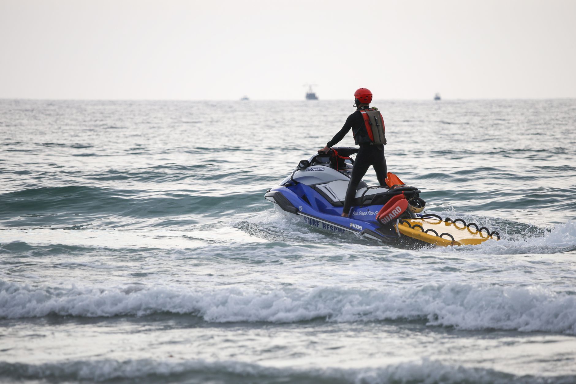 A lifeguard on a jet ski patrols the ocean to ensure swimmer safety during daytime.