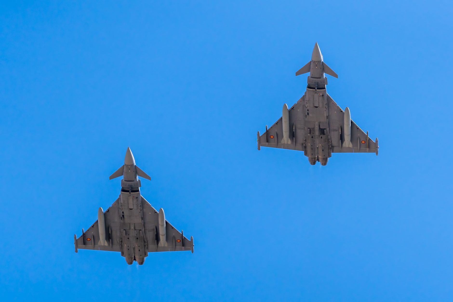 Two Eurofighter jets flying in formation against a clear blue sky.