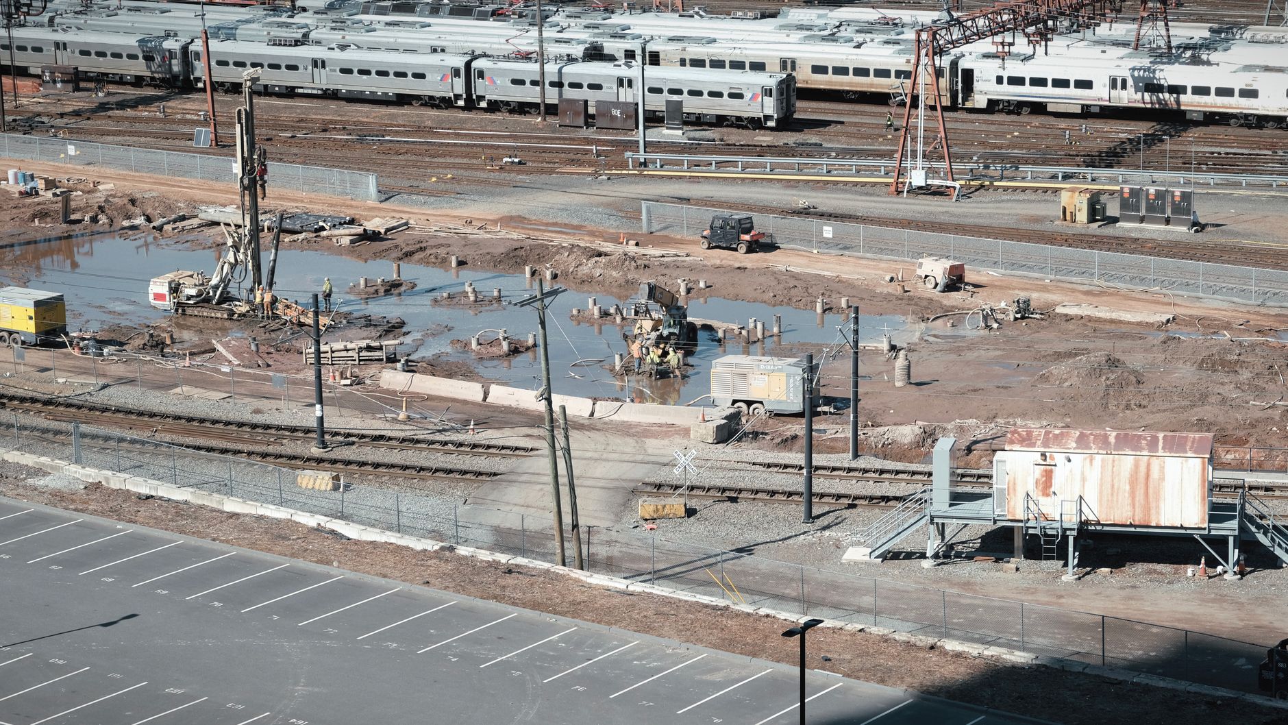 Aerial view of a construction site adjacent to railway tracks with workers and machinery.