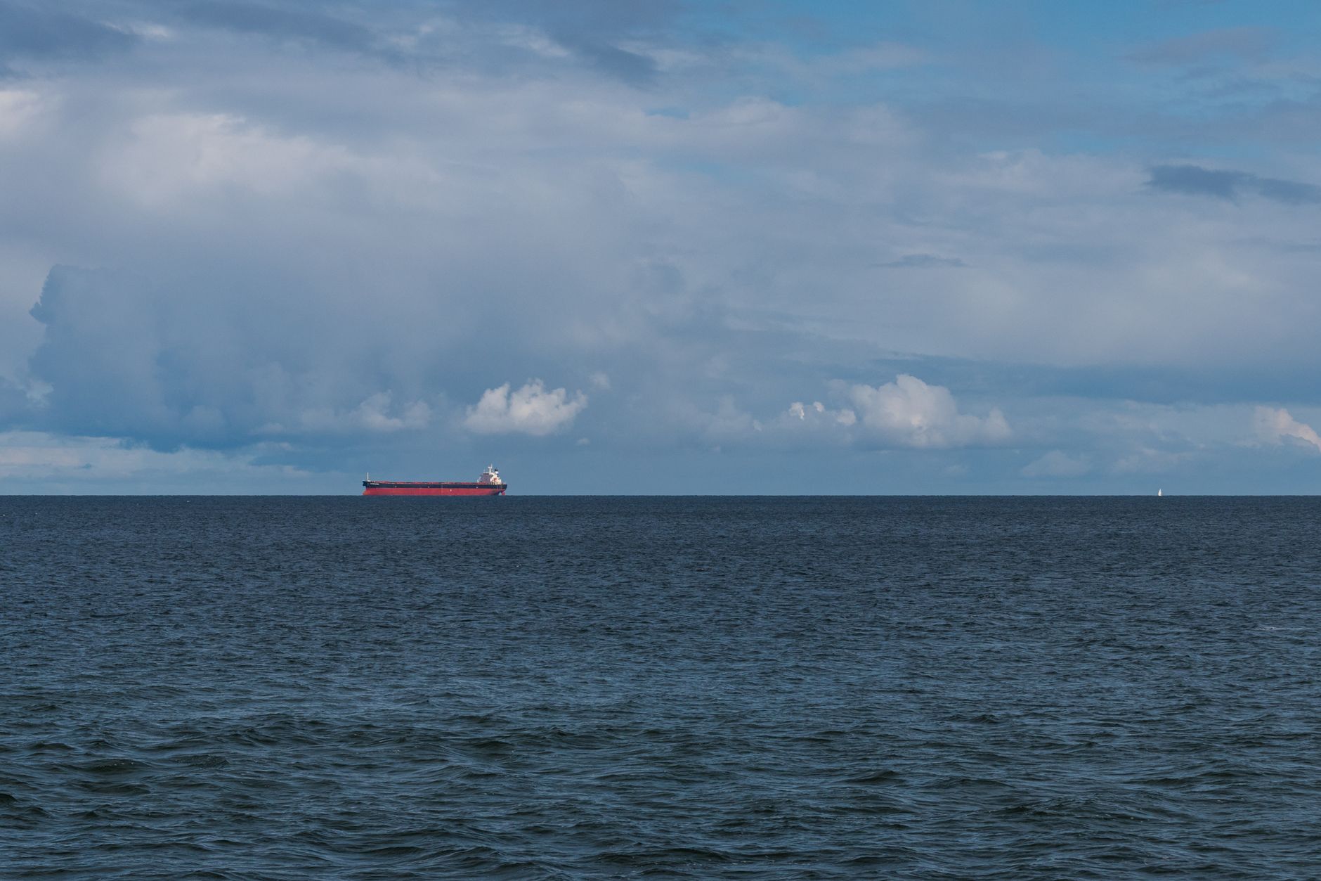 A red cargo ship sails under a cloudy sky on the Baltic Sea near MV, Germany.