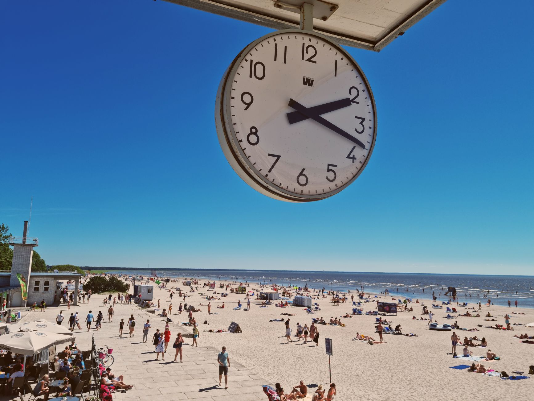 A lively summer day at Pärnu Beach captured under a clear blue sky with a prominent clock view.
