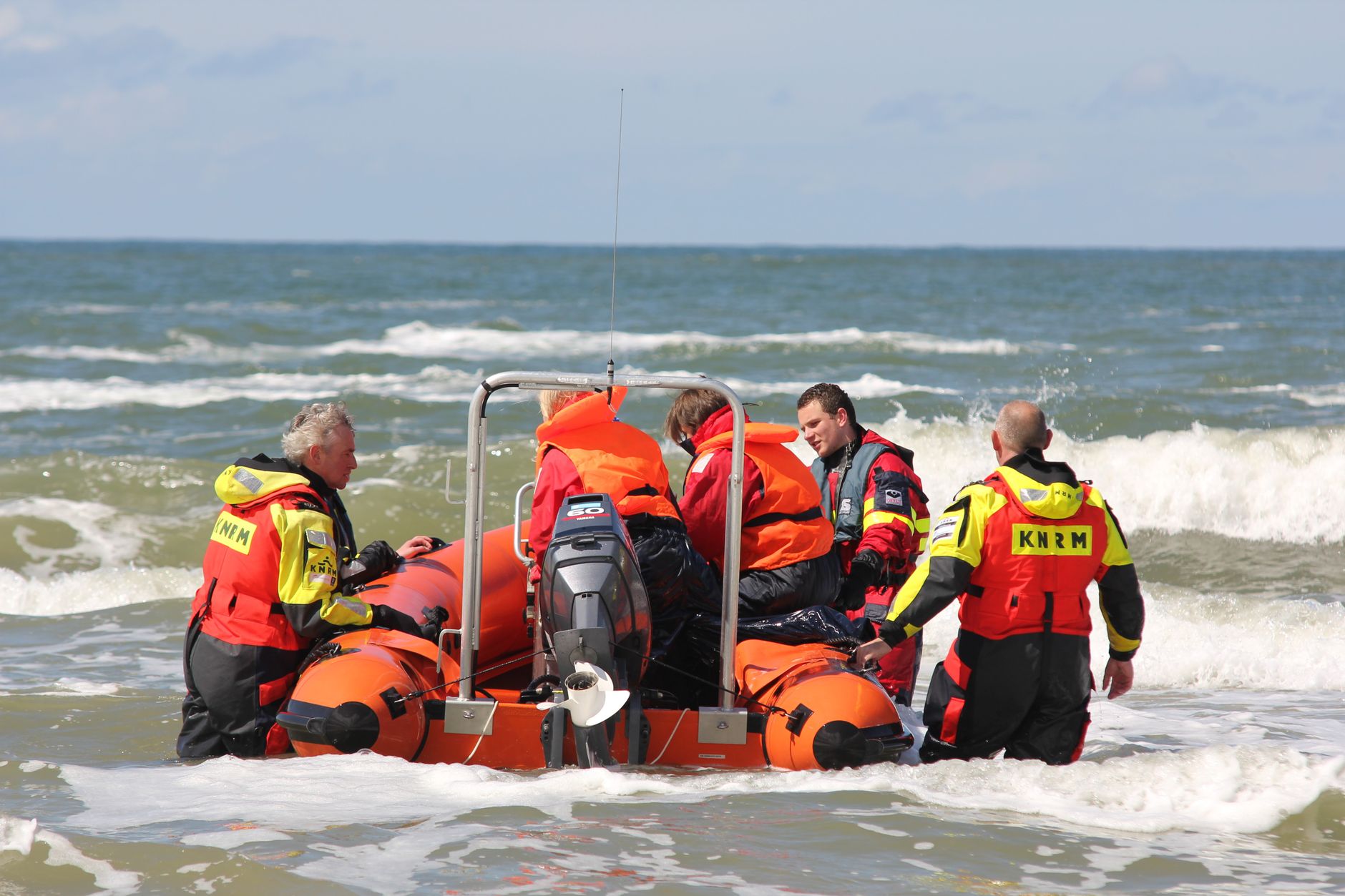 Coast guard team with orange rescue boat preparing for sea operation.