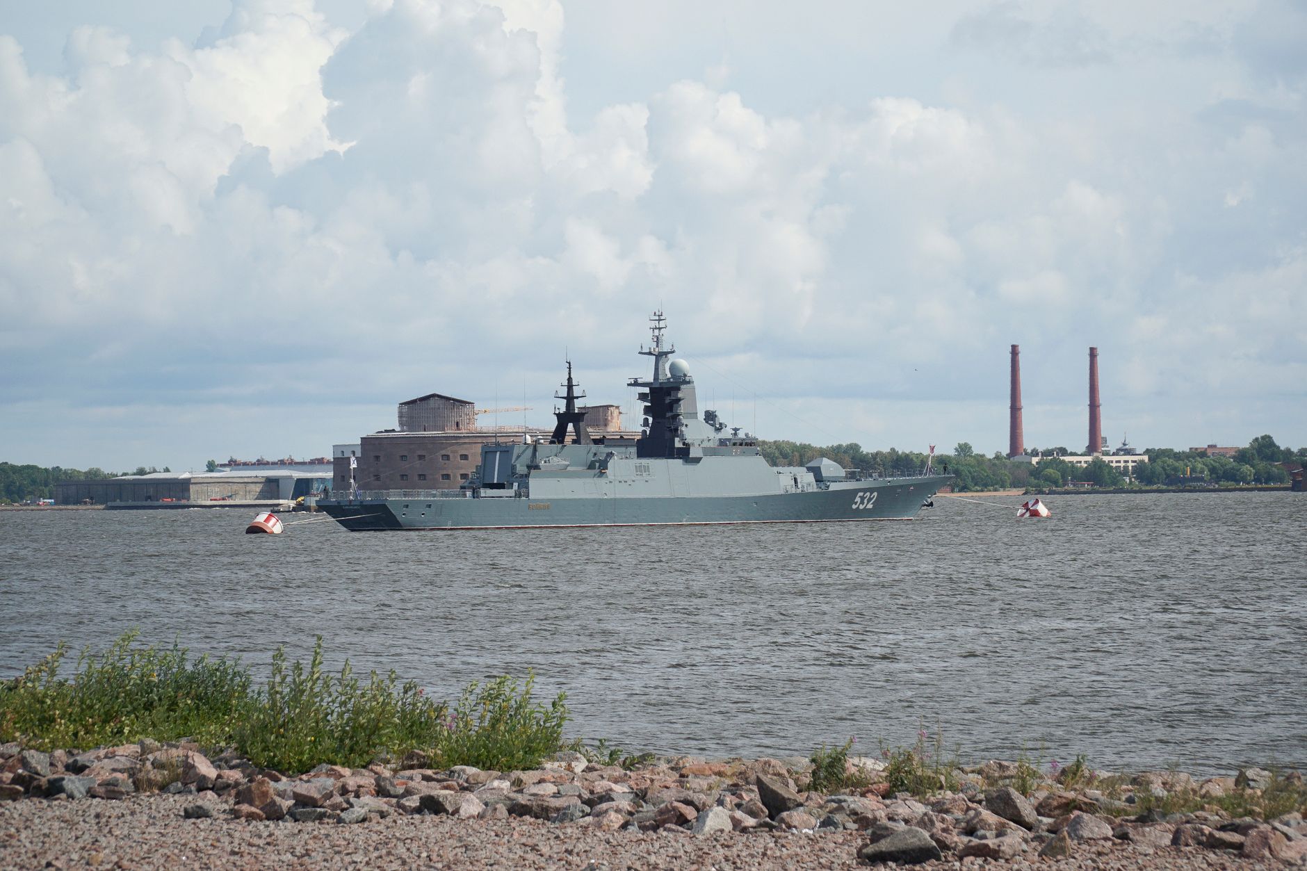A military warship sailing in the waters of Saint Petersburg, Russia, with industrial background.