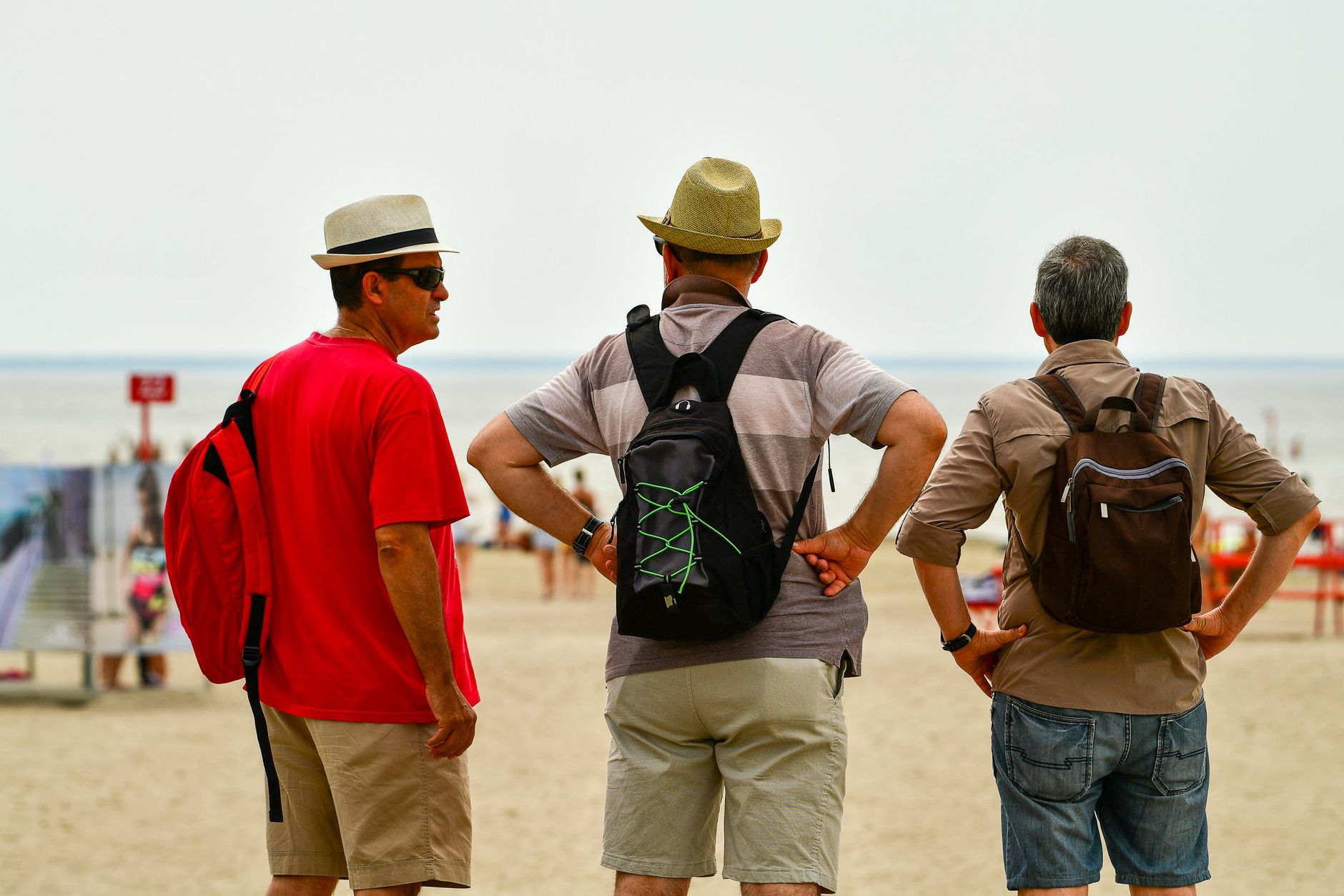 Three men in summer attire enjoying a sunny day at Pärnu Beach, Estonia.