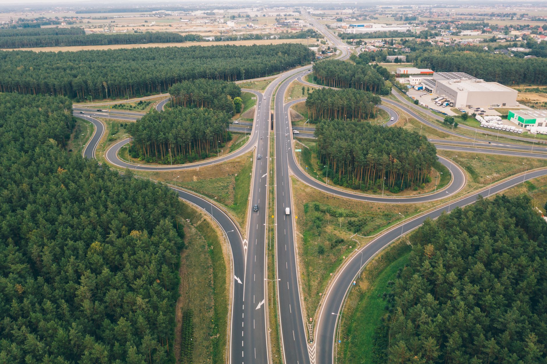 Aerial view of a highway interchange surrounded by forest near Poznań, Poland, showcasing modern transportation infrastructure.