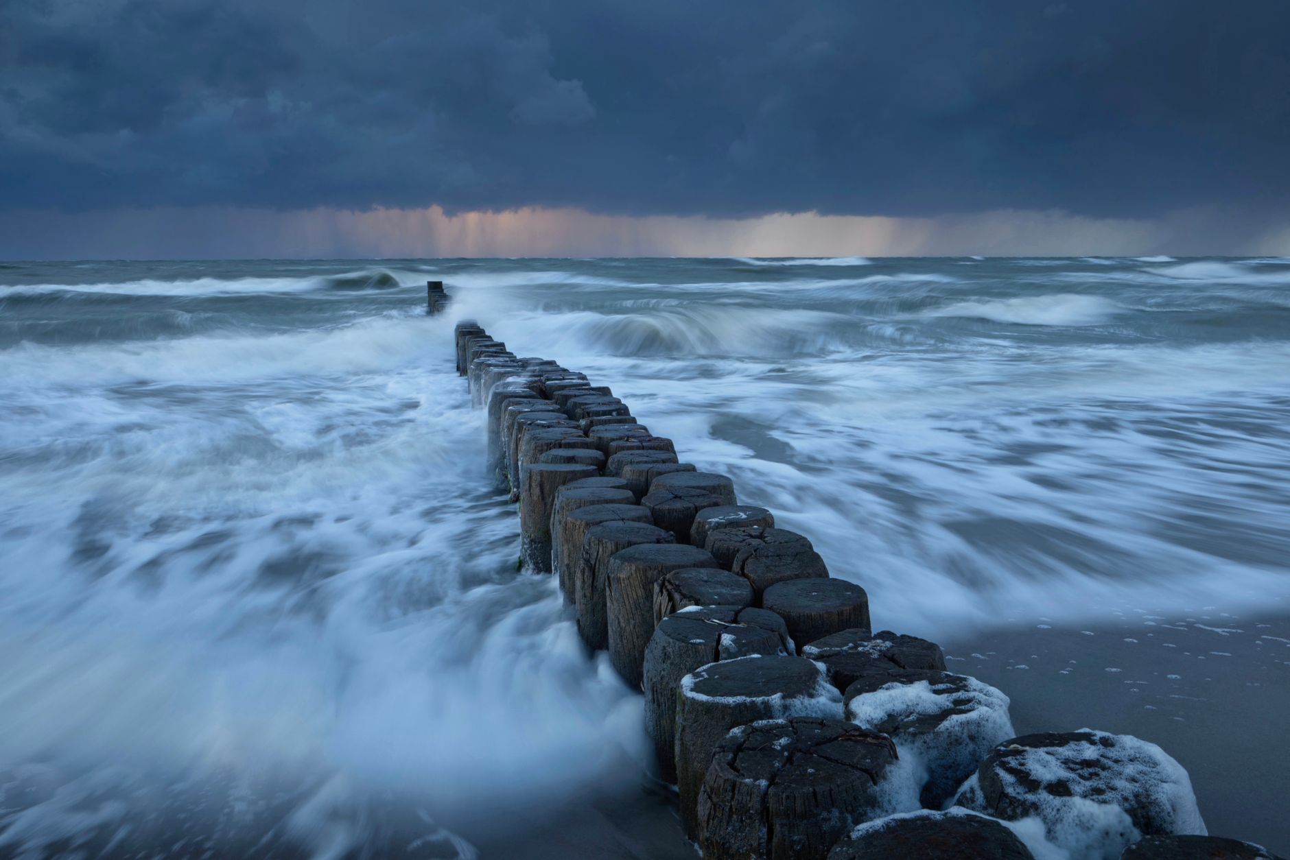 Captivating view of waves crashing against a breakwater under a stormy sky.