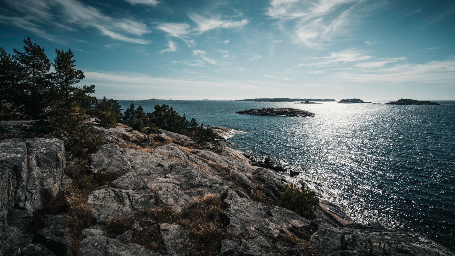 Breathtaking view of Finland's rocky coastline with sparkling sea and distant islands.