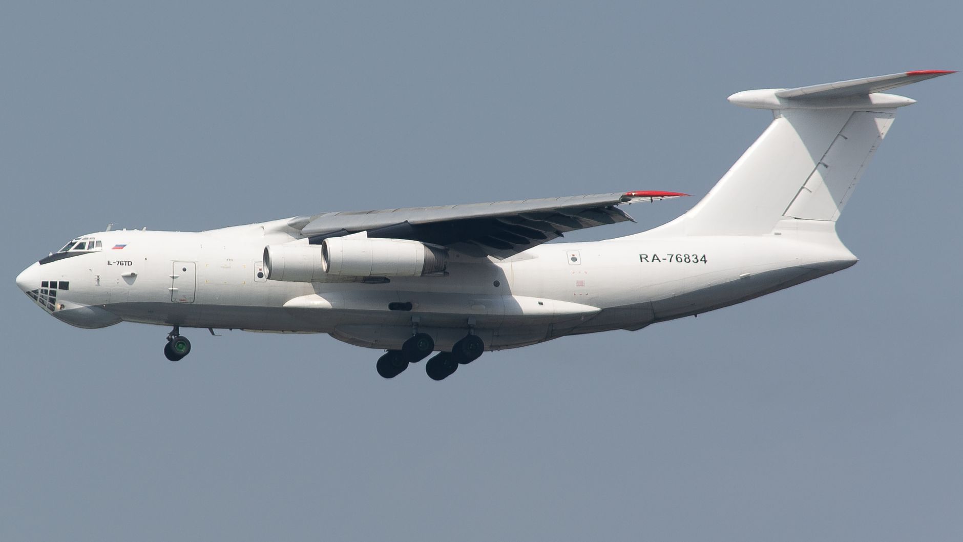 Ilyushin Il-76TD cargo aircraft flying against a clear blue sky.