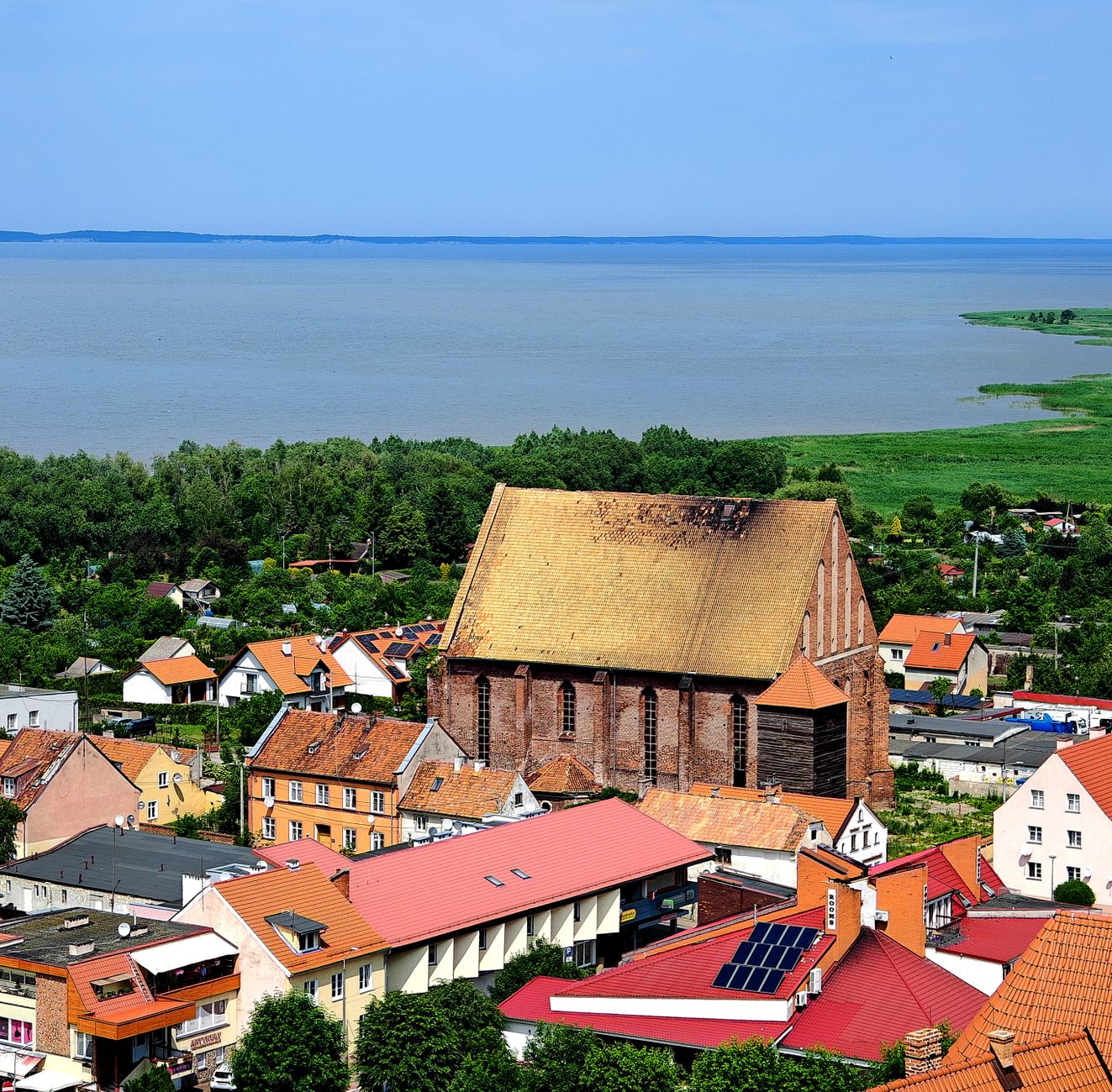Scenic aerial view of Frombork featuring a historic church and Vistula Lagoon, Poland.