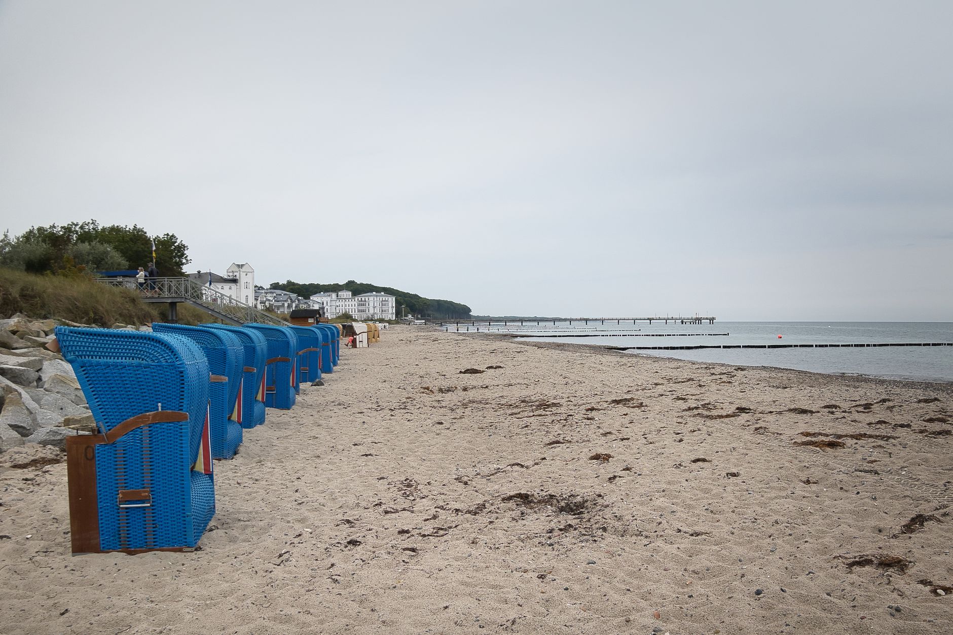 A tranquil Bad Doberan beach scene with blue Strandkorb and pier in early autumn.