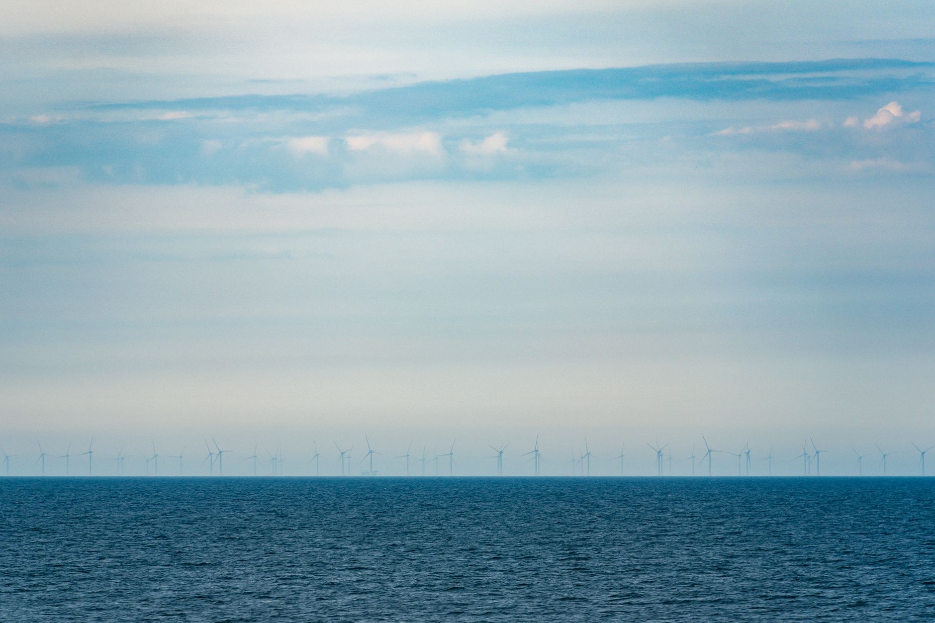 A tranquil view of an offshore wind farm on a clear day showcasing renewable energy and natural beauty.
