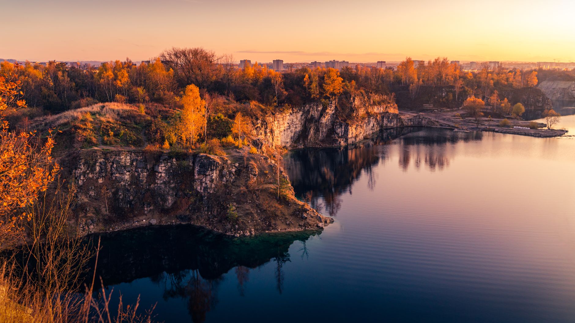 Peaceful sunset view of Zakrzówek Lake with autumn foliage in Kraków, Poland.