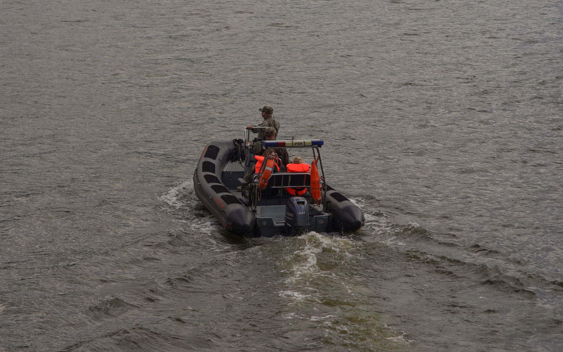 A motorboat with a soldier navigating through the river in Wrocław, showcasing boating activities.
