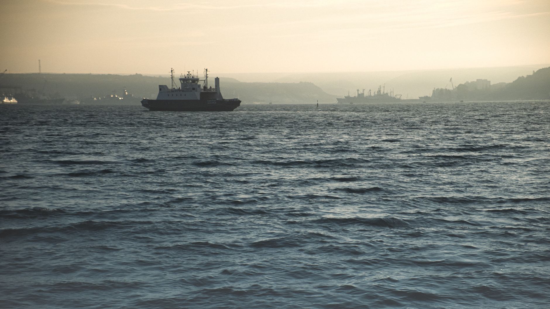A serene view of a ferry sailing on the ocean during a calm dusk, creating a tranquil maritime setting.